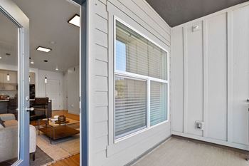 A modern living room with a glass door leading to a kitchen.